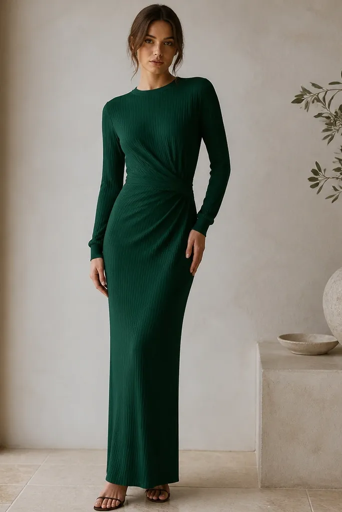 A deep emerald long sleeve maxi dress made of ribbed jersey, with a wrap-style front at the waist and a straight skirt. The neckline is modest, and the sleeves taper to a fitted cuff.