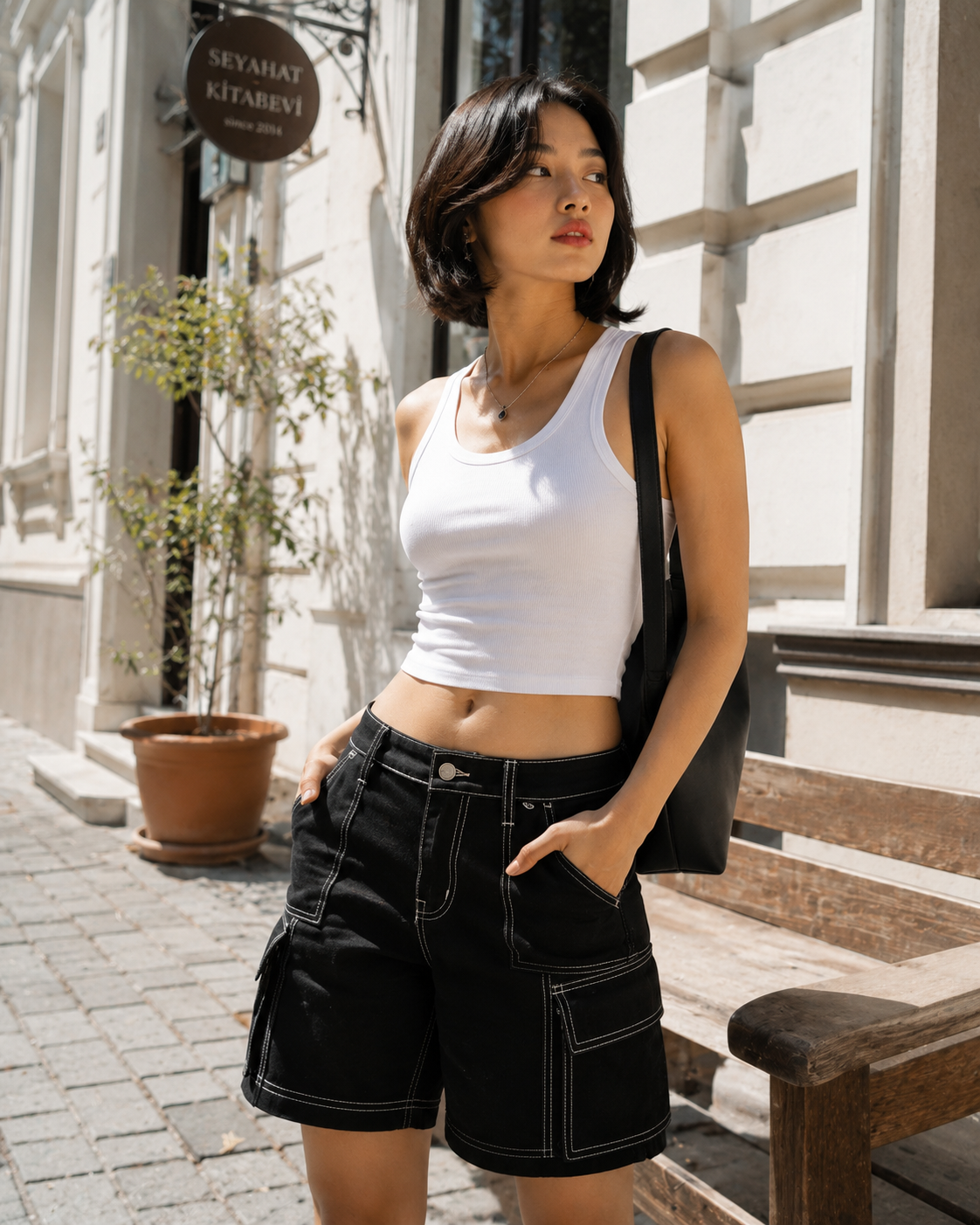 A white tank worn over black cargo shorts; visible cargo pockets and seams; white sneakers; sunglasses; a relaxed but tidy silhouette.