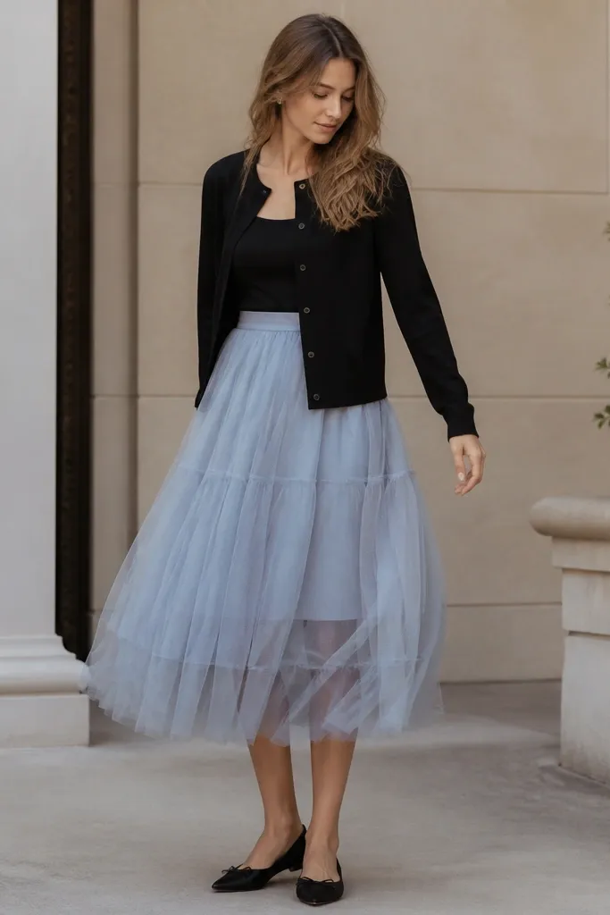 A black cardigan over a baby blue tulle-layered skirt; the photo shows a simple black top underneath and black flats.