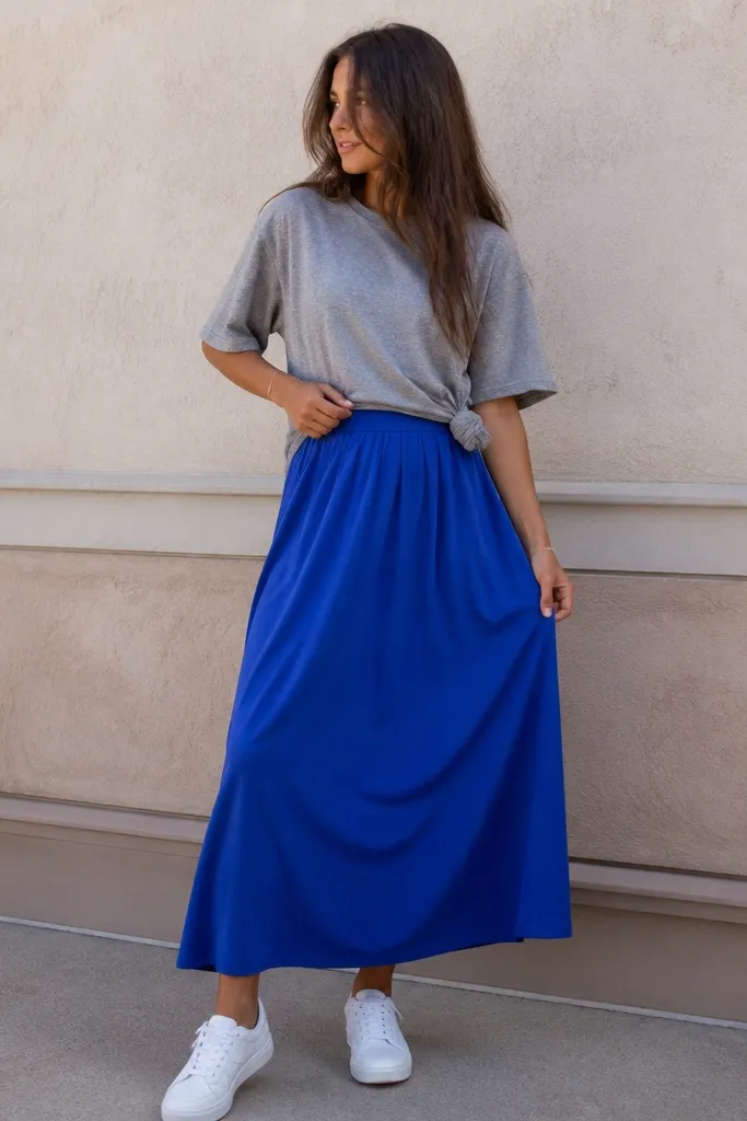 A bright cobalt-blue skirt worn with an oversized heather gray T-shirt. The tee is front-tucked with one small knot at the side, and the shoes are white sneakers.
