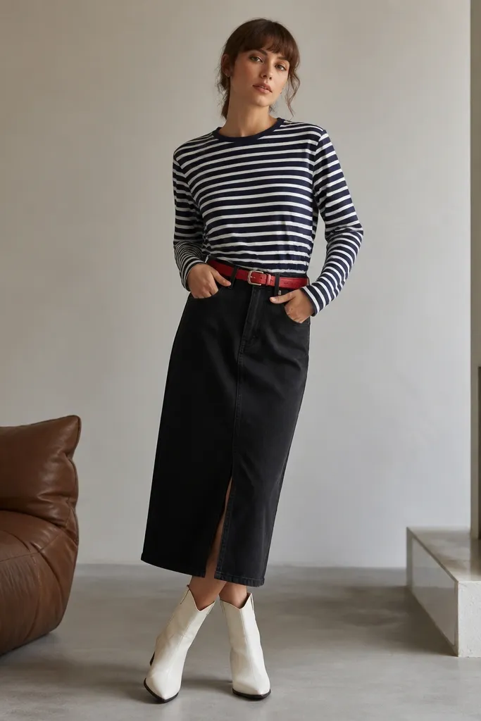 A navy and white striped long-sleeve shirt is worn with a black denim midi skirt and a red leather belt; the outfit includes white ankle boots.
